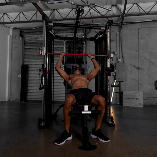 Lifestyle image of a model performing a Smith Benchpress with the Inspire Fitness FT2 Functional Trainer