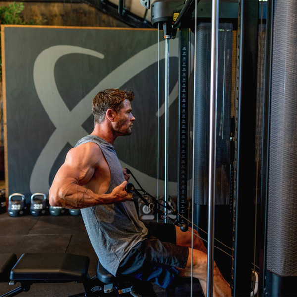 Chris Hemsworth seated and performing a cable row on the Inspire Fitness FT2 PRO Functional Trainer.
