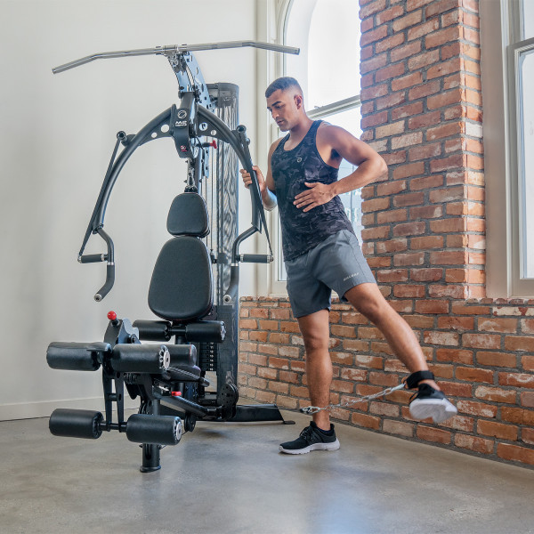 A person performing a standing leg kick with the Inspire Fitness M2 Multi-Gym