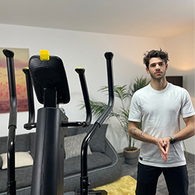 Model standing beside an exercise machine in a Kinomap coaching video 