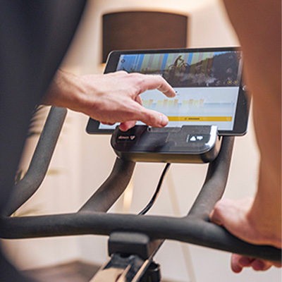 Model using Kinomap structured workouts on a tablet during indoor cycling