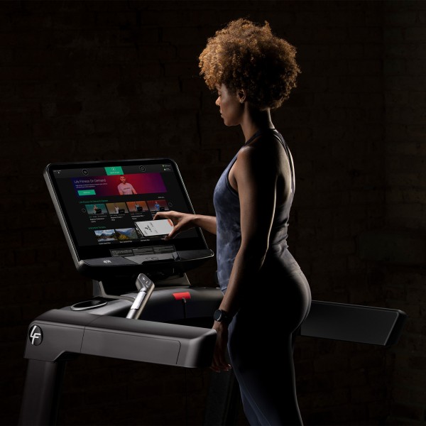 Exerciser putting the phone on the Life Fitness Integrity+ Treadmill