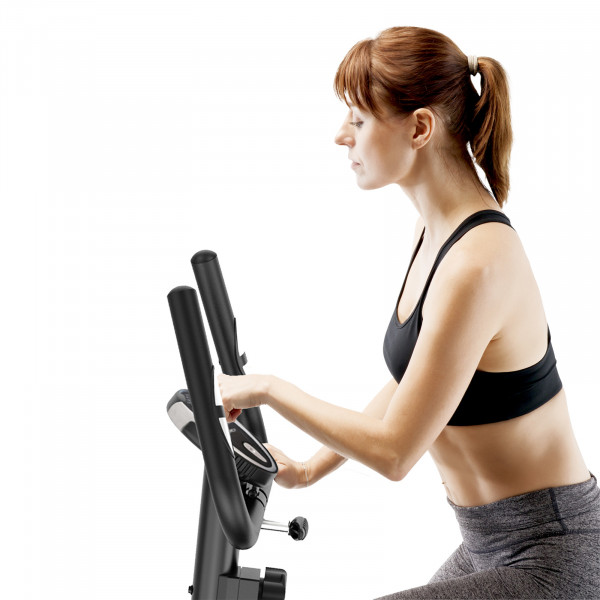 Model adjusting the LCD console on the Marcy Arrow Compact Upright Exercise Bike before a workout session