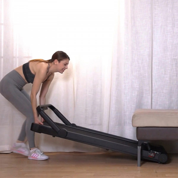 Model moving the Marcy Walk N Run Walking Pad Treadmill into storage position