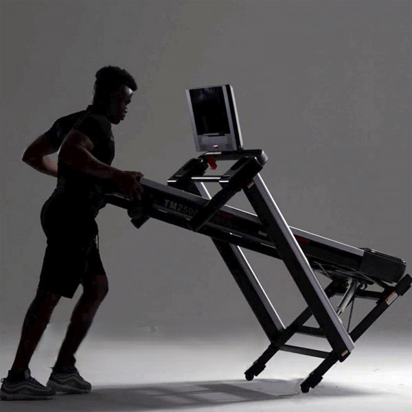 Model storing the Marcy Cross Country Power Fold Treadmill in folded position