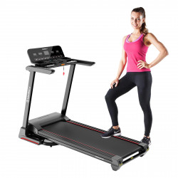Model standing beside the Marcy Interceptor Compact Treadmill to demonstrate product size and scale