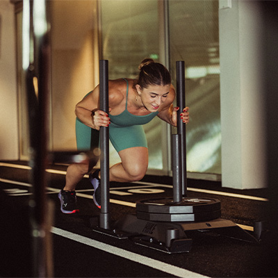 Image of a model pushing the Nike Strength Weight Sled over turf