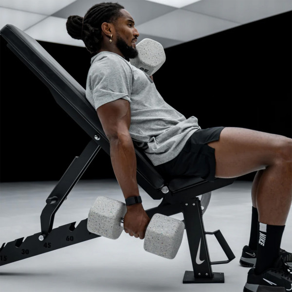 Person training on the Nike Strength Adjustable Weight Bench with dumbbells in an incline position