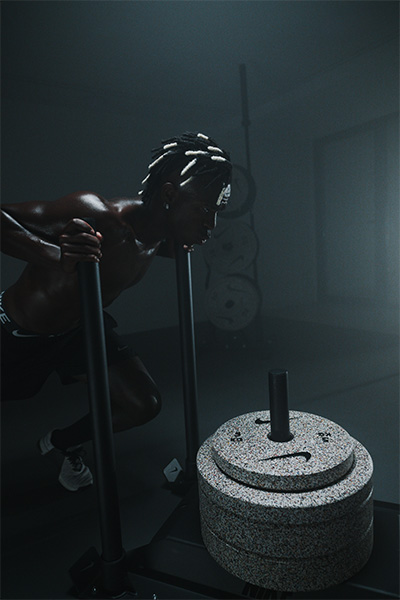 Model pushing a sled loaded with Nike Strength Grind Bumper Plates