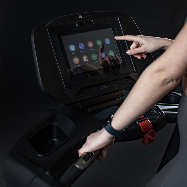 Model using the touchscreen on the NoblePro Elite E8ix Treadmill