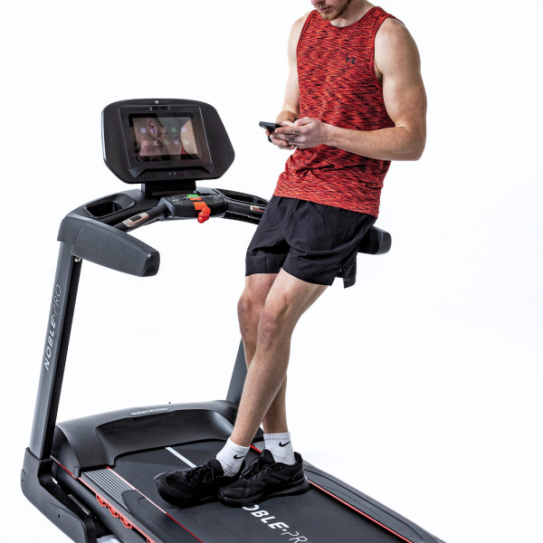 Model using a smartphone on the NoblePro Elite E8ix Treadmill