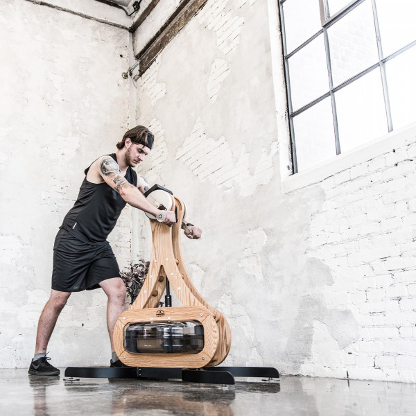 User exercising on the NOHRD WaterGrinder Arm Bike in a home gym