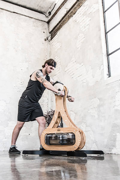 User exercising on the NOHRD WaterGrinder Arm Bike in a home gym