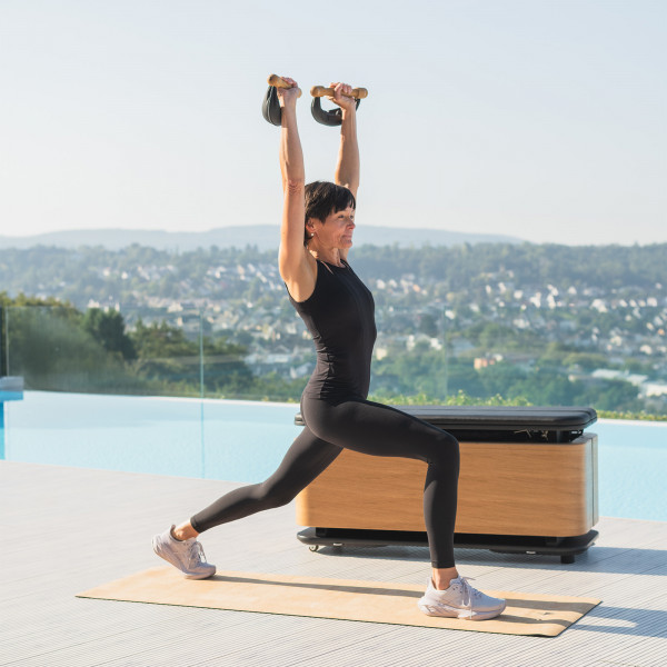 User performing overhead lunge with SwingBells.
