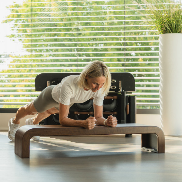 User holding plank position on NOHRD StepBox step panel.