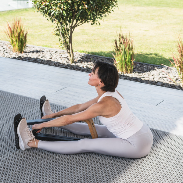 User seated upright on the NOHRD SpineStretch mid-stretch.