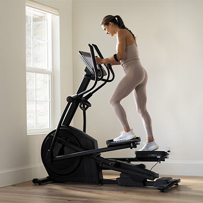 Person stepping on the NordicTrack AirGlide 14i Elliptical in a side view during a home workout 