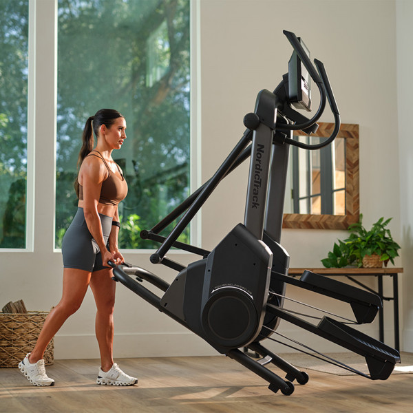 Side view of a person moving the NordicTrack X16 Elliptical Cross Trainer.
