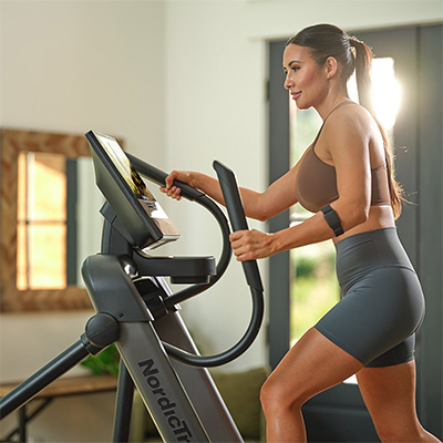 Model working out on NordicTrack X16 Elliptical while holding the moving handlebars 