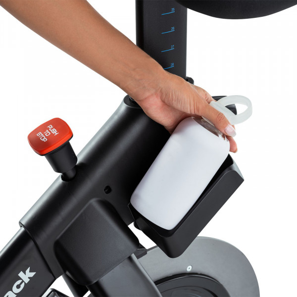 Closeup of a hand placing a bottle in the holder on the NordicTrack X24 Bike