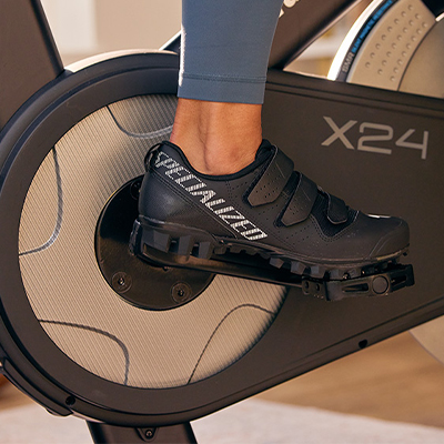 Closeup of cycling shoes clipped into pedals on the NordicTrack X24 Bike 