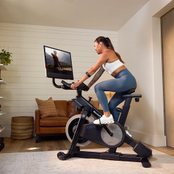 Side view of a model cycling on the NordicTrack X24 Bike in a home environment