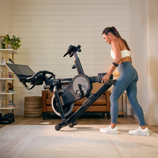Model moving the NordicTrack X24 Bike using transport wheels in a home setting