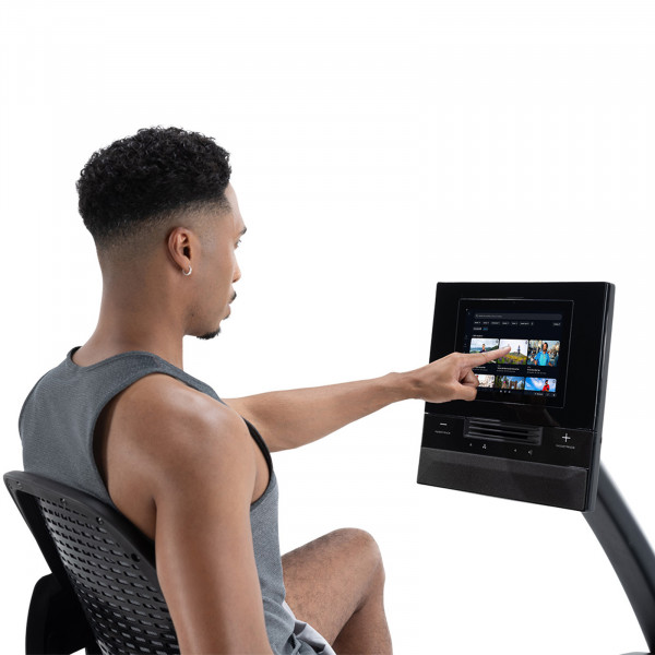 Person interacting with the console on the NordicTrack 10 Recumbent Bike.
