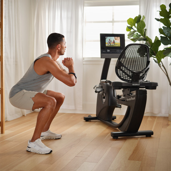 Model doing squats near NordicTrack 10 Recumbent Bike