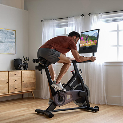 Model riding NordicTrack 24 Studio Exercise Bike in a forward lean position during workout 