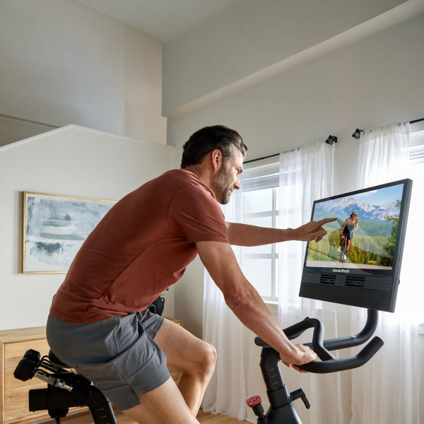 Model tapping touchscreen on NordicTrack 24 Studio Exercise Bike during workout