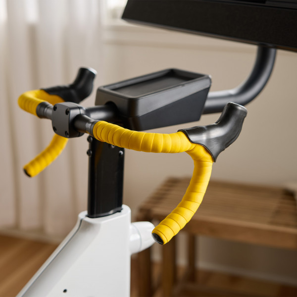 Close-up of the yellow drop handlebars and storage tray on the NordicTrack Tour de France Indoor Bike.