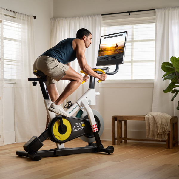 Person cycling on the NordicTrack Tour de France Indoor Bike while following a workout on the screen.
