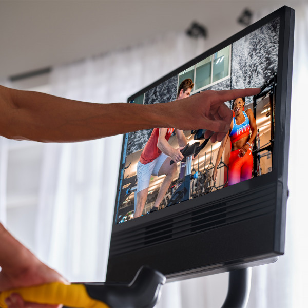 Close-up of a hand selecting a workout on the touchscreen of the NordicTrack Tour de France Indoor Bike.