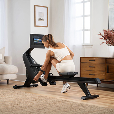 Model adjusting the foot straps on the NordicTrack RW700 Rowing Machine 
