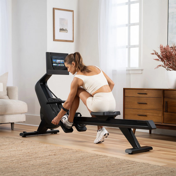 Model adjusting the foot straps on the NordicTrack RW700 Rowing Machine