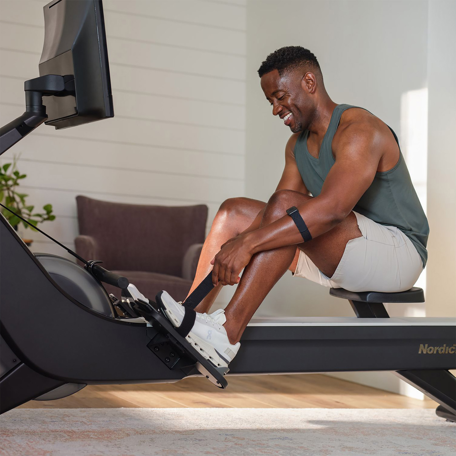 Close-up of model adjusting foot straps on NordicTrack RW900 Rower before workout 