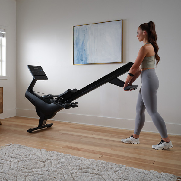 A product image of the NordicTrack RW300 Rower in use with a model utilising the transport wheels.