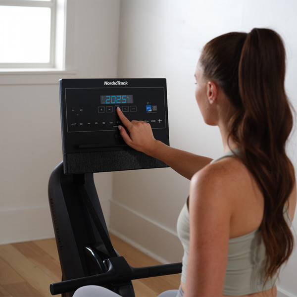 A lifestyle image of the NordicTrack RW300 Rower in use with a model using the console.