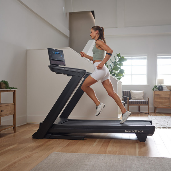 Side view of a person running on the NordicTrack Commercial LE Treadmill.
