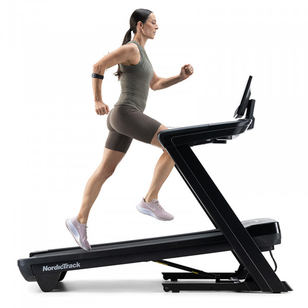 Side view of a person running on the NordicTrack Commercial 1250 Treadmill at an incline.