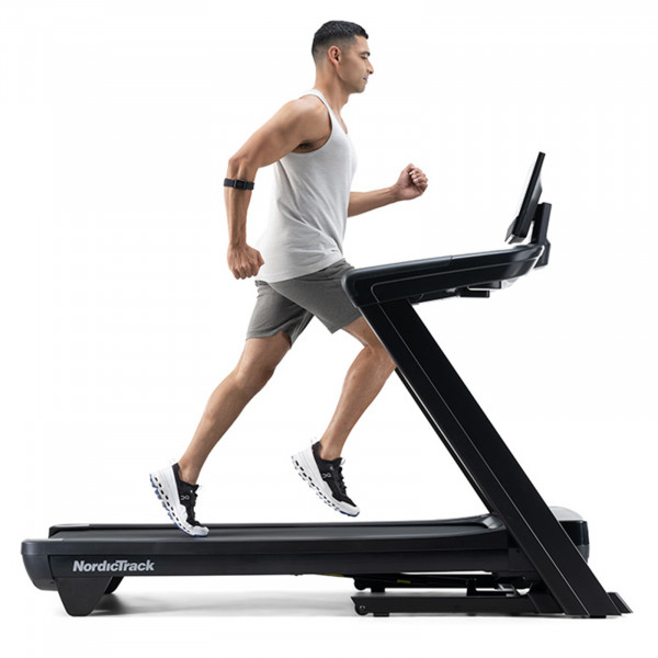 Side view of a person running on the NordicTrack Commercial 1250 Treadmill.
