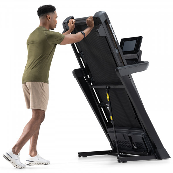 Person folding up the NordicTrack T Series 10 Treadmill.
