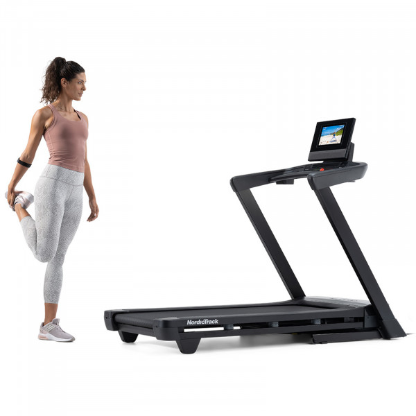 Person stretching next to the NordicTrack T Series 10 Treadmill.
