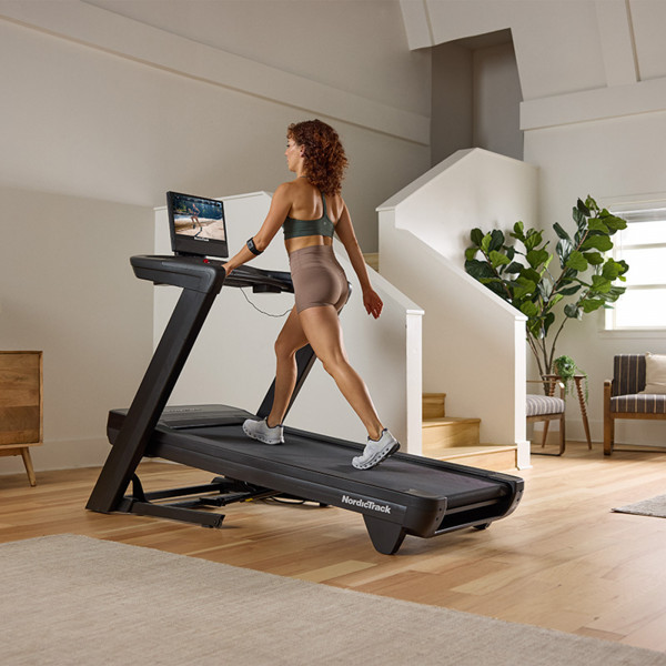 Side view of a person walking on the NordicTrack Commercial 1750 Treadmill at an incline.