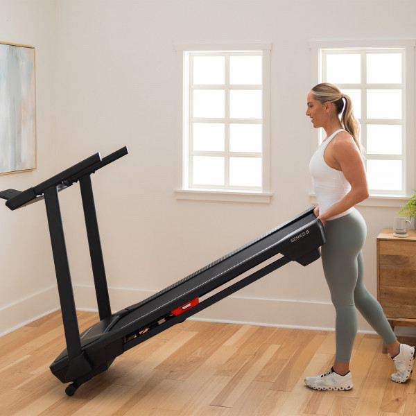 Side view of a person moving the NordicTrack T Series 5 Treadmill.
