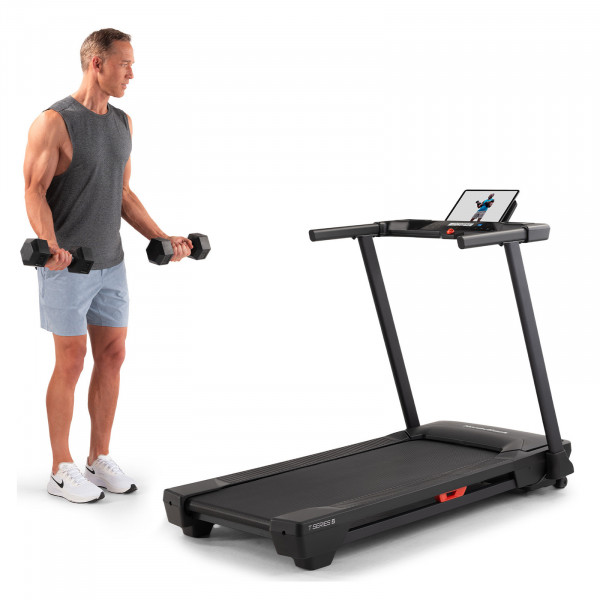 Model doing bicep curls next to the NordicTrack T Series 5 Treadmill