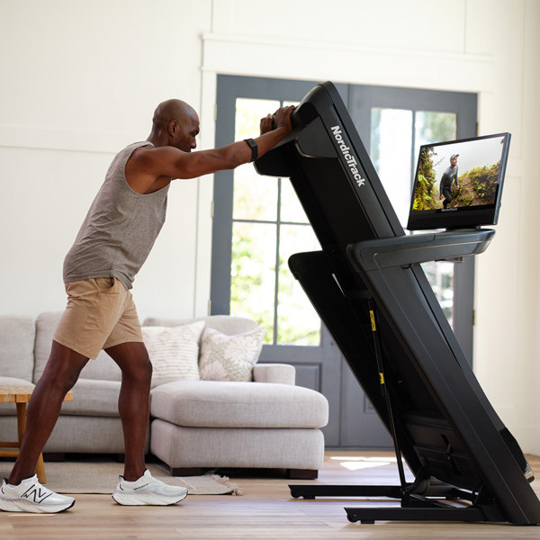 Person folding the NordicTrack Commercial 2450 Treadmill for storage.