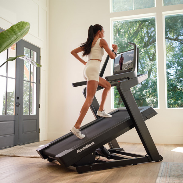 Angled view of a person running on the NordicTrack Commercial 2450 Treadmil at an incline.