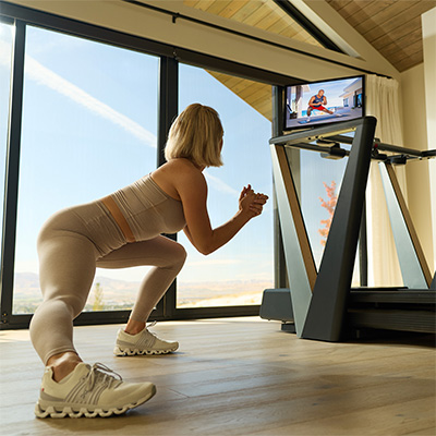 Model performing a floor exercise beside the NordicTrack Ultra 3 Treadmill with pivoted screen  